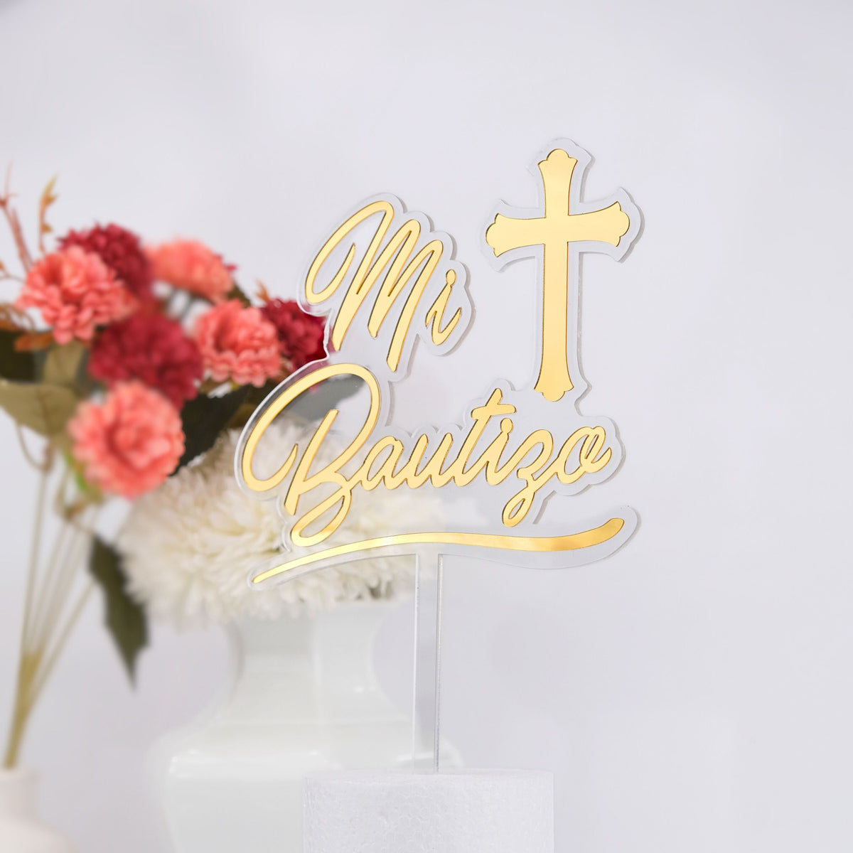 Gold 'Mi Bautizo' cake topper with a cross on a white background