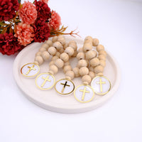 Wooden rosary beads with cross charms on a white plate with red flowers in the background