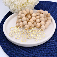 Wooden mini rosaries with gold cross charm on a white plate with white flowers in the background.
