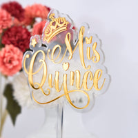 Decorative cake topper with 'Mis Quince' text and crown on a white background with flowers.