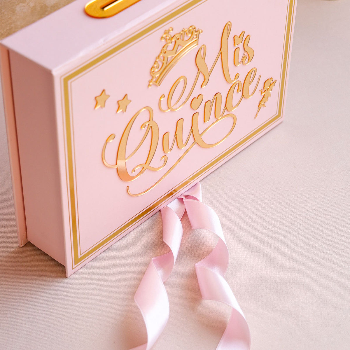 Pink gift box with gold text and a hand holding a pink ribbon.