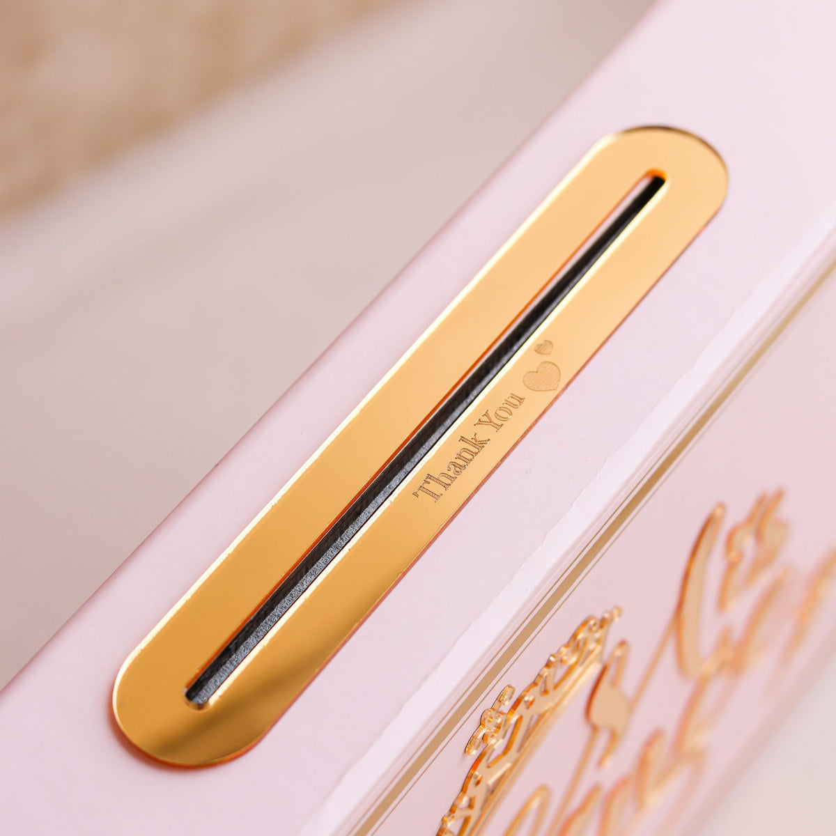 Close-up of a pink product with a gold 'Thank You' label on a beige background