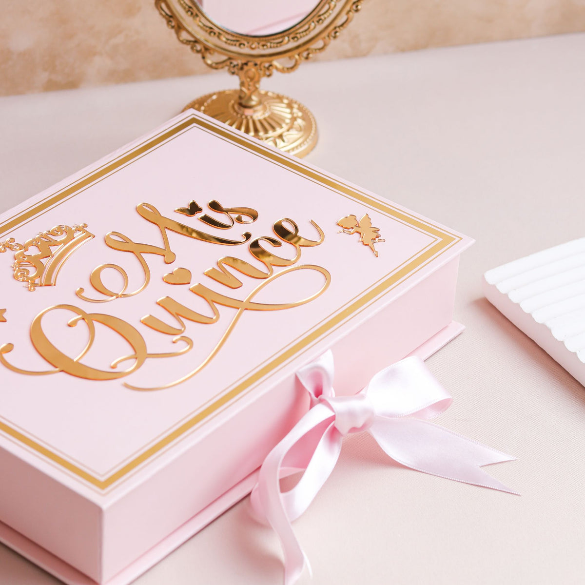 Pink box with gold text and a pink ribbon on a light background