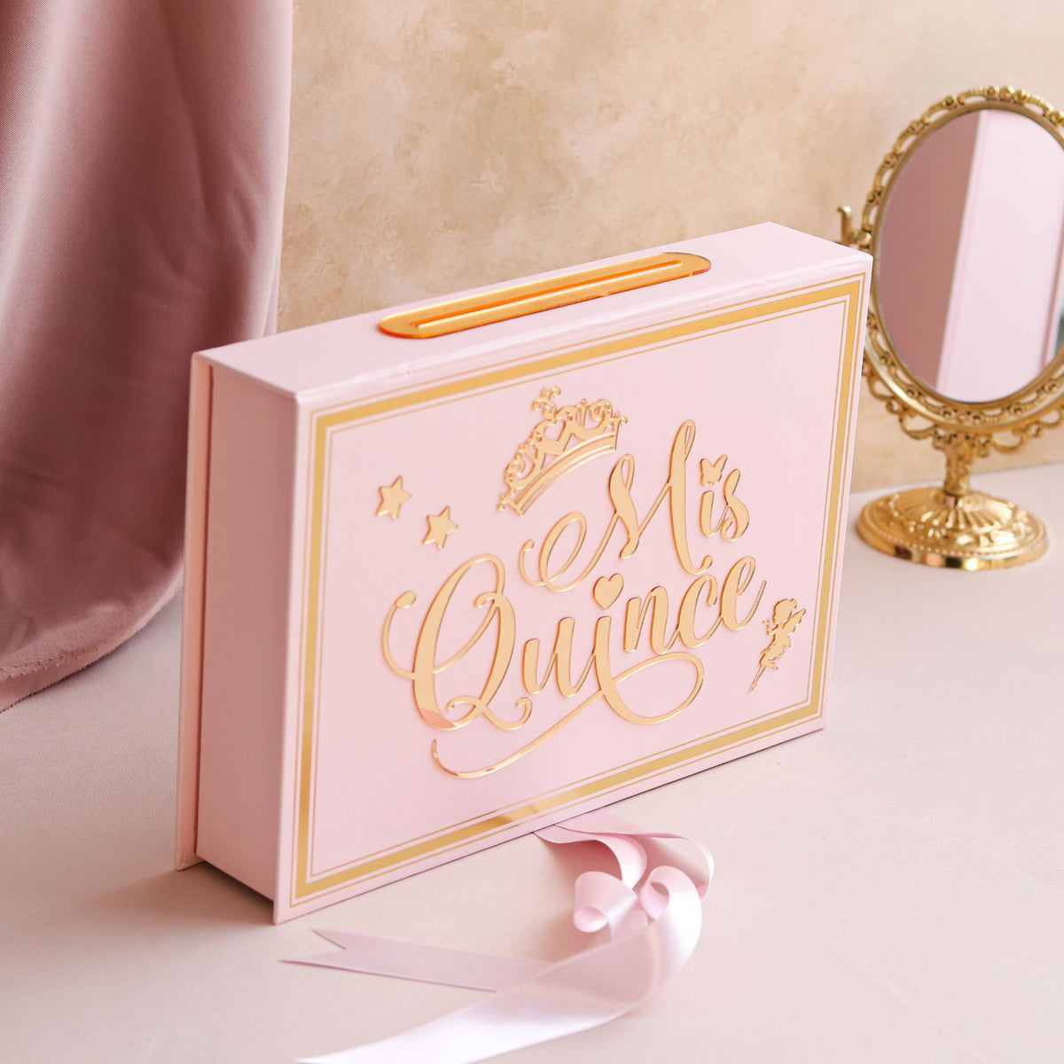 Pink gift box with 'Mis Quince' text on a decorative surface with a mirror.