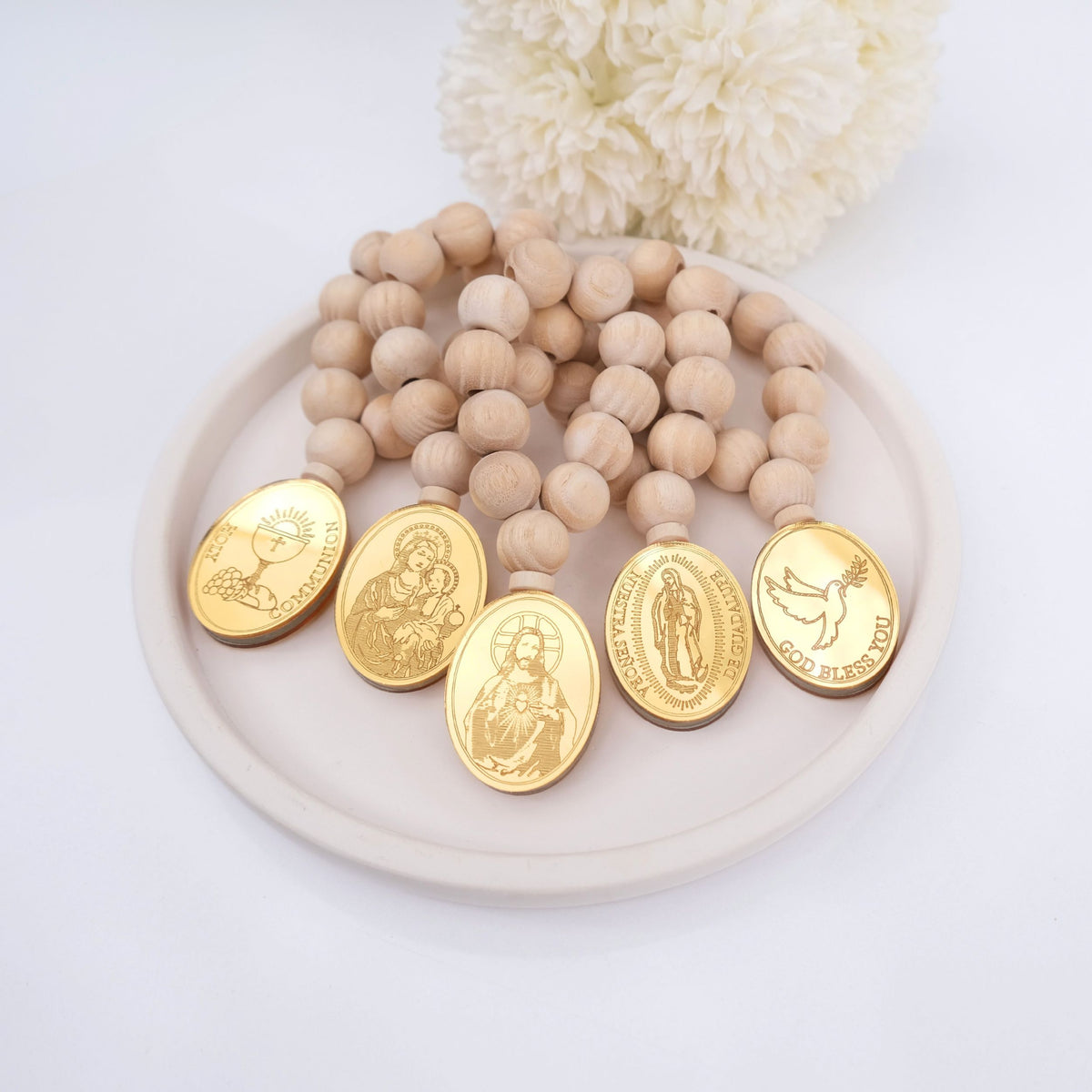 Wooden beaded mini rosary catholic favors with gold religious medallions on a white plate