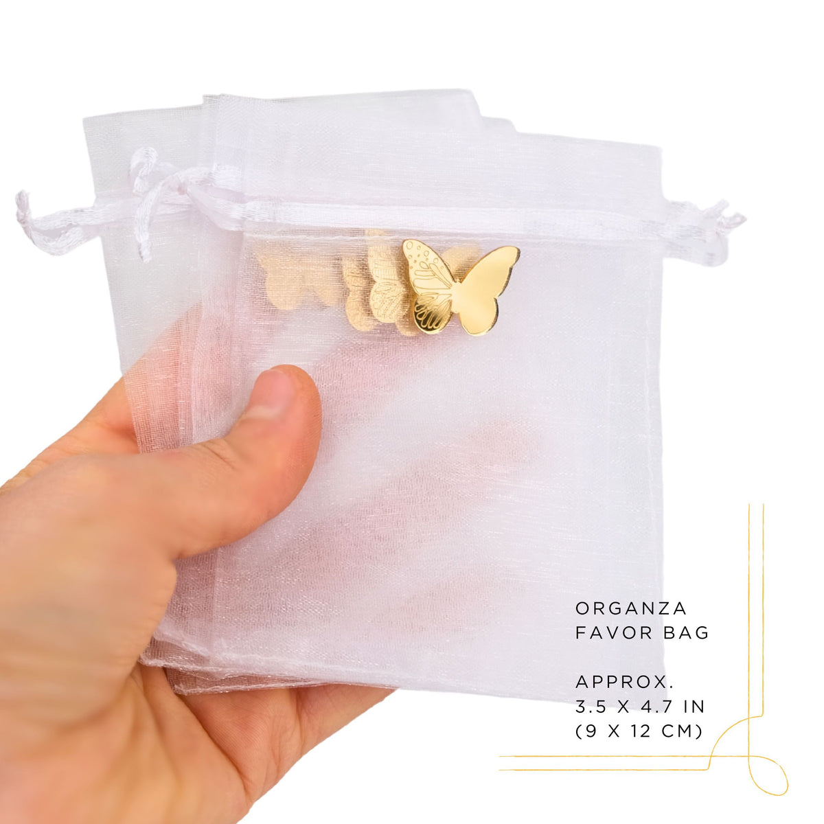 Hand holding a white organza favor bag with gold butterfly charm on a white background