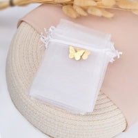 White butterfly charm white organza favor bag on a textured surface