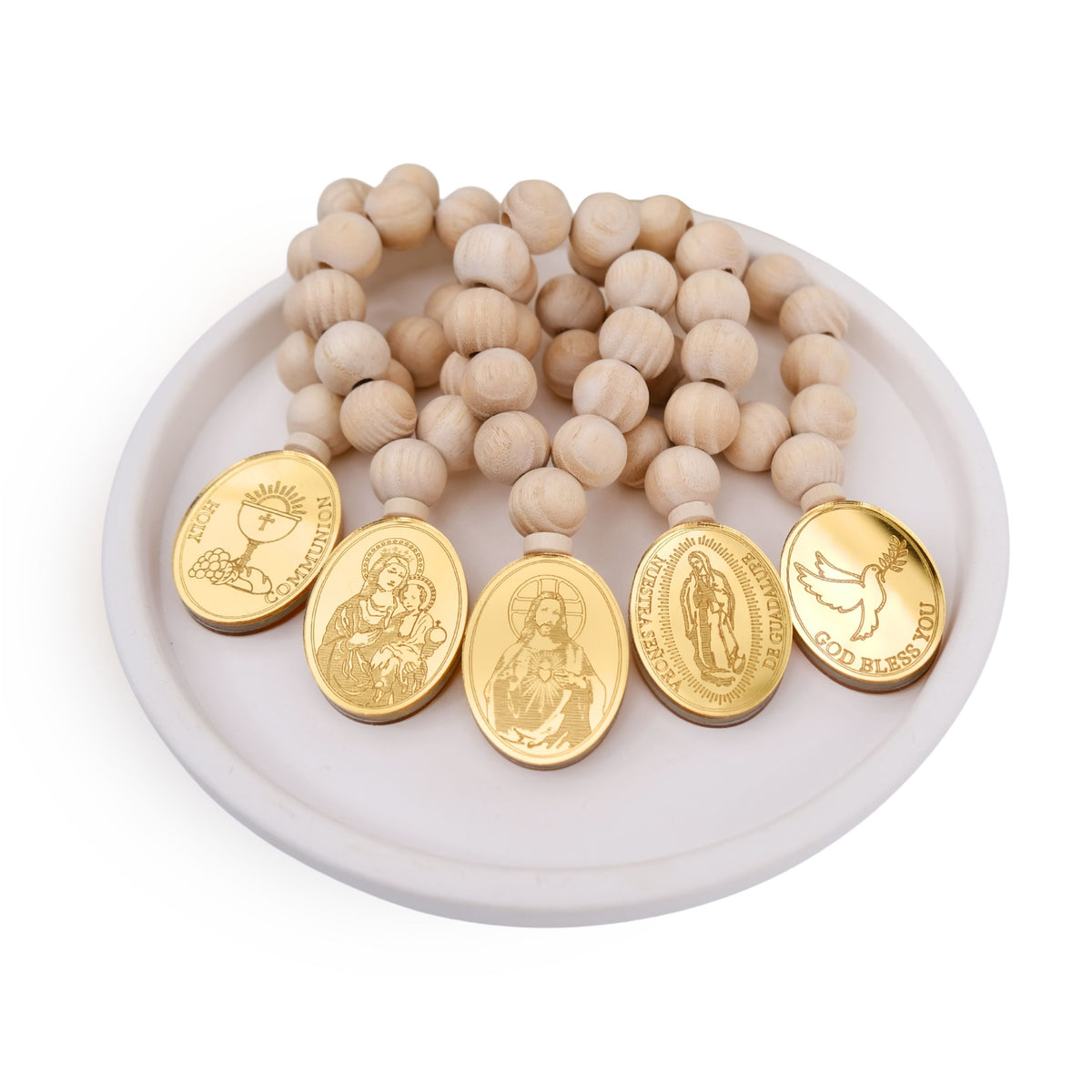 Wooden beaded mini rosary favors with gold religious medallions on a white dish