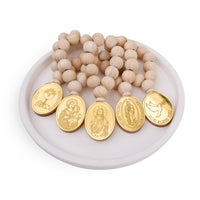 Wooden beaded mini rosary favors with gold religious medallions on a white dish